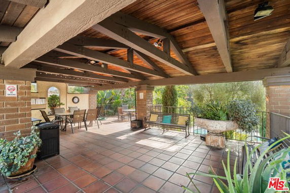 Rooftop area with wooden beams, seating, and surrounding greenery.