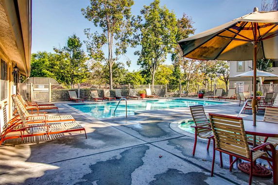 Outdoor swimming pool area with lounge chairs and umbrellas.