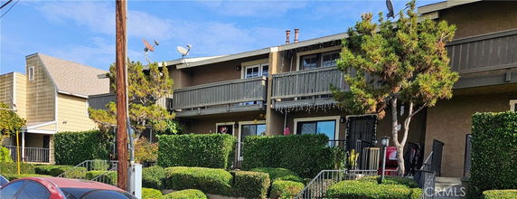 Front view of a two-story residential building with balconies and greenery.