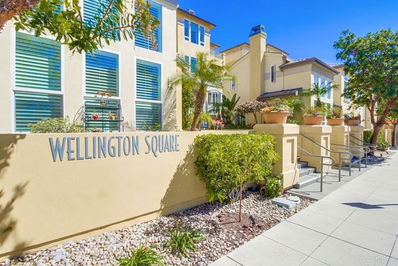 Front view of a multi-story building with large windows and a sign reading 'Wellington Square'.