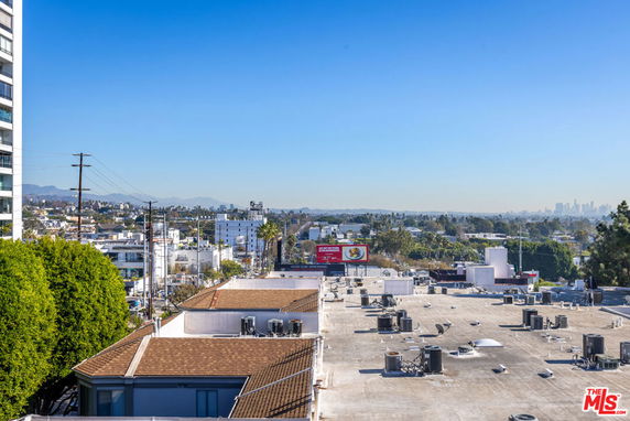 Panoramic view of urban surroundings with rooftops and distant cityscape.