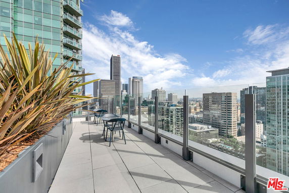 Rooftop view of city skyline with glass railings and outdoor seating.
