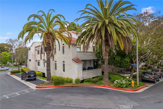 Front view of a two-story house with palm trees and a corner location.