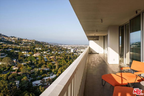Panoramic view from a balcony overlooking a hilly residential area.
