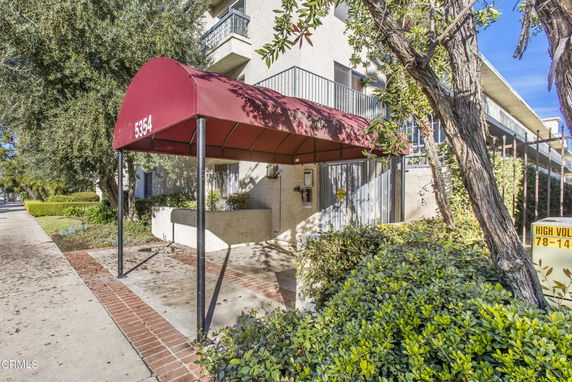 Front view of a building with a red awning and balcony.