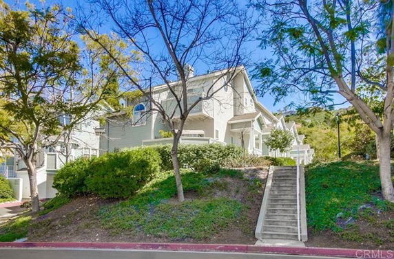 Front view of a multi-story house with stairs leading up to the entrance.