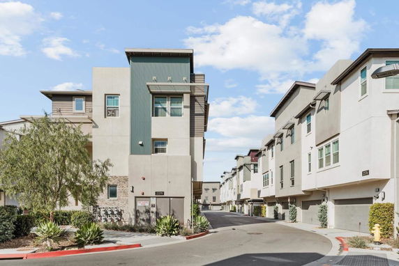 Front view of a modern multi-story residential building along a street.