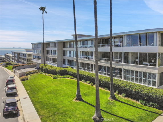 Front view of a multi-story apartment building with large windows and a landscaped lawn.