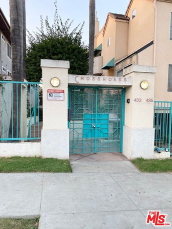 Front view of a building entrance with a gated entry labeled 'CROSSROADS' and light fixtures on either side.