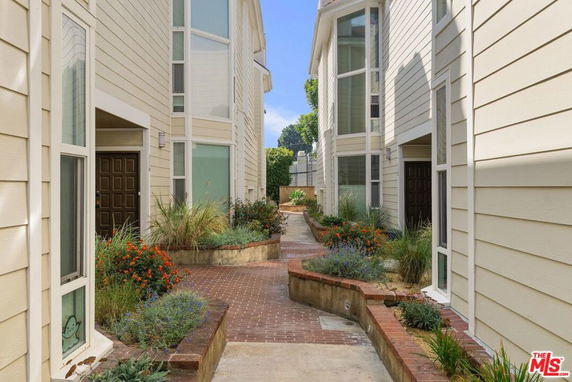 Front view of a modern multi-story building with large windows and landscaped walkway.
