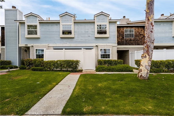 Front view of a two-story townhouse with a white fence and blue siding.