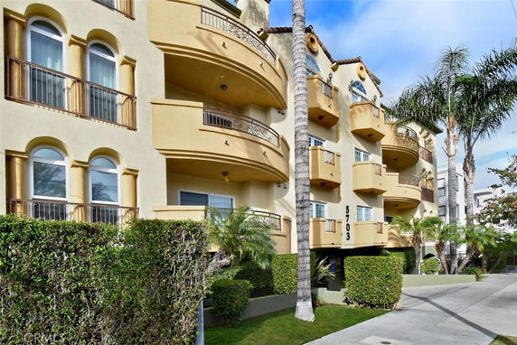 Front view of a multi-story building with balconies and arched windows.