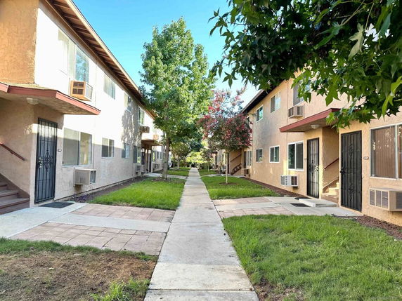 View of the front of two-story apartment buildings with air conditioning units.