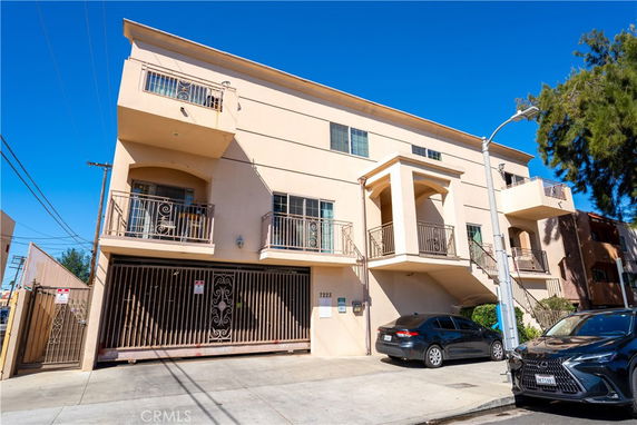 Front view of a multi-story residential building with balconies and gated entrance.