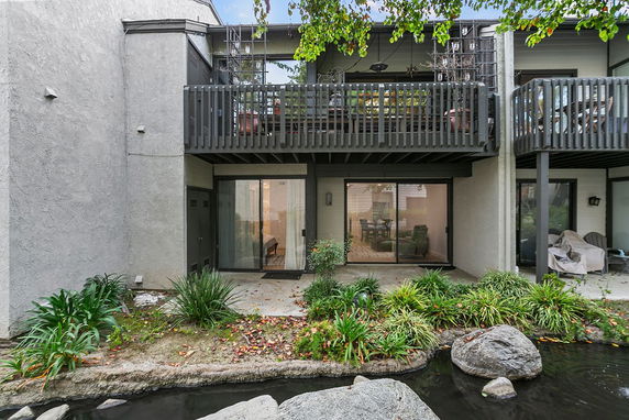 Rear view of a multi-story building with balconies and sliding glass doors.