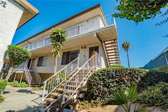 Front view of a two-story apartment building with exterior staircases and balconies.