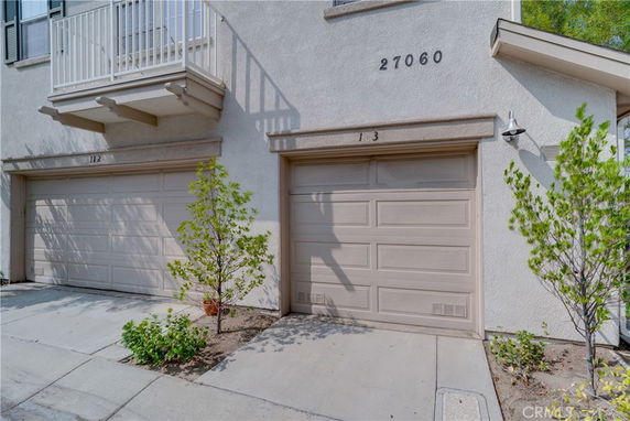 Front view of a building showing two garage doors labeled 112 and 13 beneath small balconies.