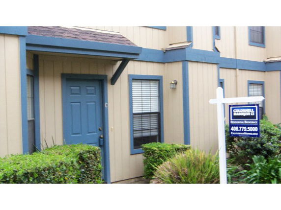 Front view of a two-story house with blue trim and a for-sale sign.