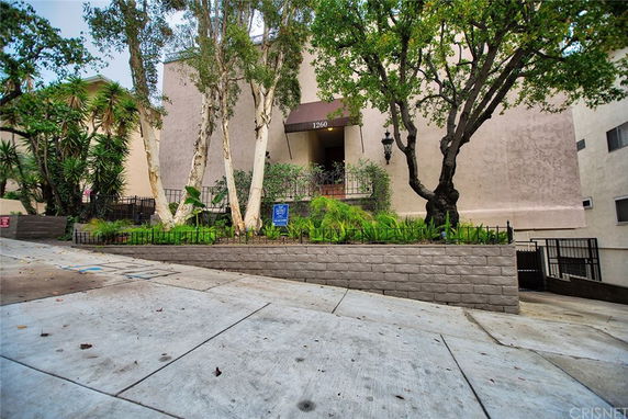 Front view of a multi-story building with trees and plants in front.