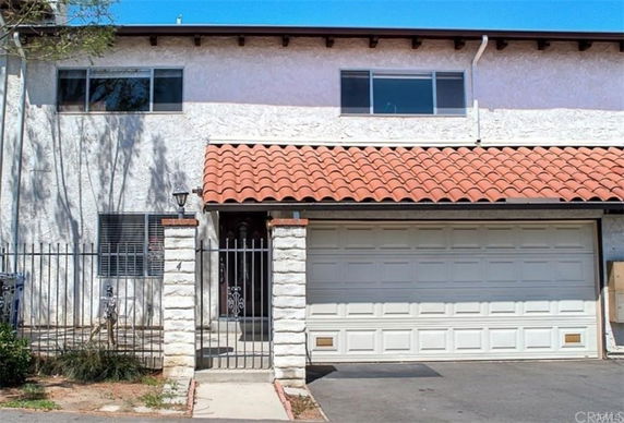 Front view of a two-story house with a garage and a fenced entrance.