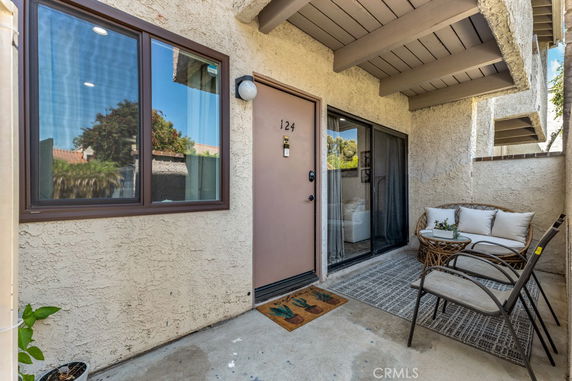 Front view of an entryway with a sliding glass door and patio furniture.