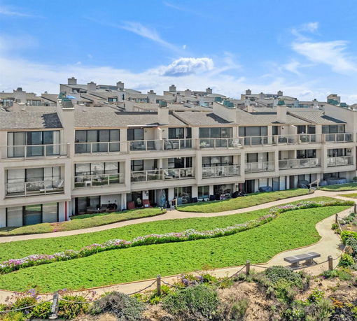 Front view of a multi-story residential building with balconies and a sloped roof.