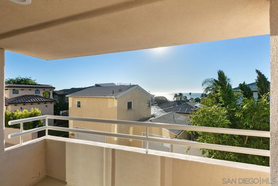 Panoramic view from a building showing rooftops and a distant ocean.