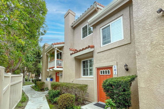 Front view of a two-story house with a red door and small balcony.