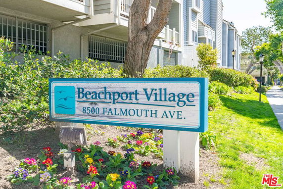 Front view of a multi-story residential building with a sign reading 'Beachport Village 8500 Falmouth Ave.'