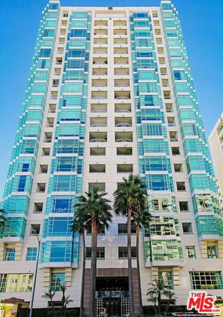 Front view of a multi-story modern building with glass balconies and tall windows.