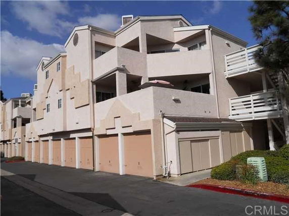Front view of a multi-story apartment building with garages on the ground level.
