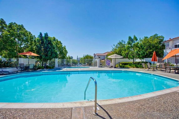 Outdoor swimming pool area with surrounding lounge chairs and umbrellas.