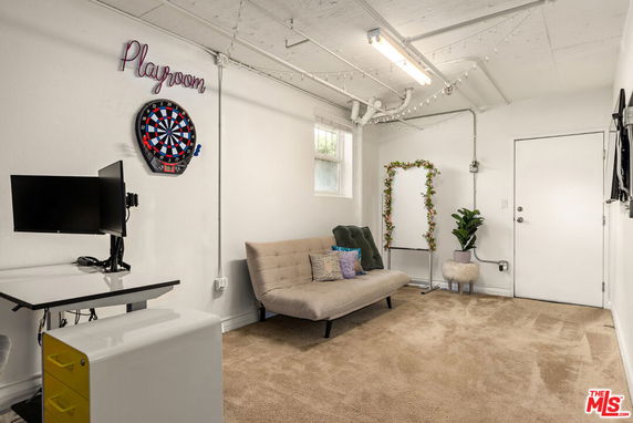Room with a dartboard, sofa, computer desk, and playful decor.