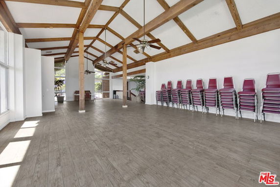 Spacious indoor recreational area with wooden beams and stacked chairs.