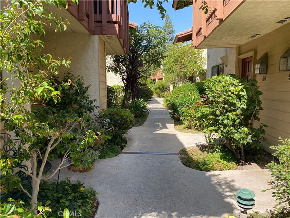 Pathway between two residential buildings with visible balconies and doors.