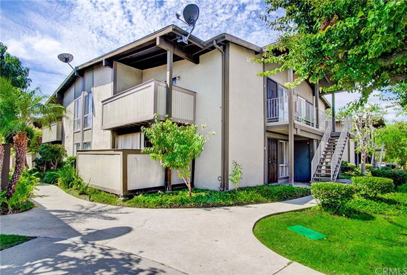Front view of a two-story residential building with balconies and external staircases.