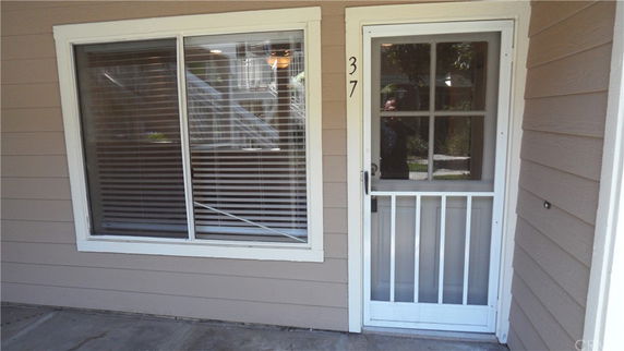 Front view of a house entrance with a window and a screen door.