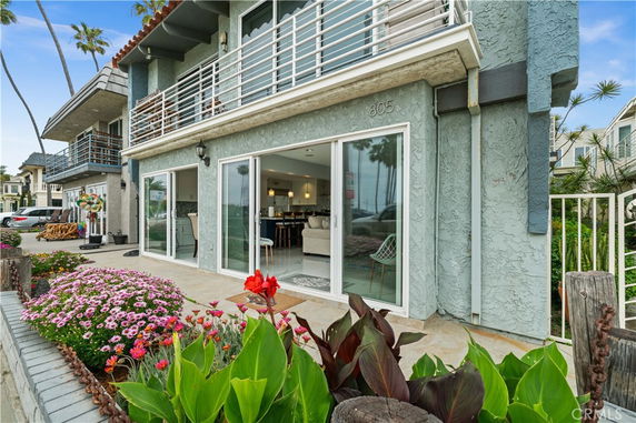 Front view of a two-story house with a balcony and sliding glass doors.