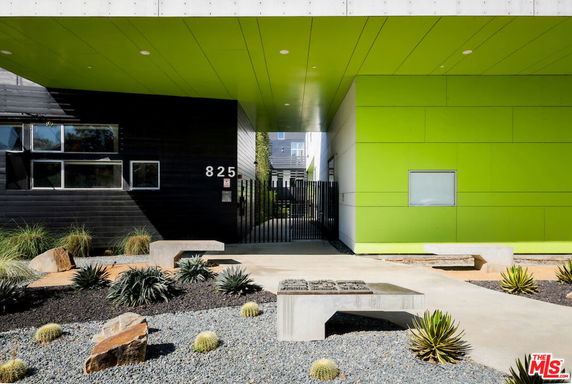 Front view of a modern building with a green facade and black accents.