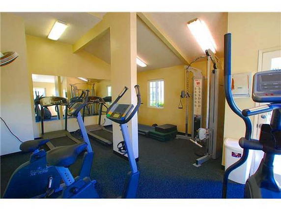 Interior view of a gym area with exercise equipment including treadmills and weight machines.