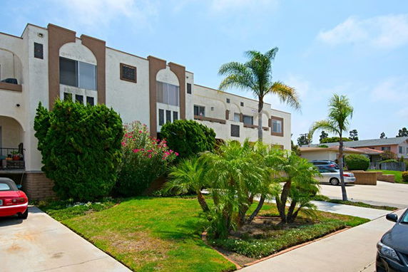 Front view of a multi-story residential building with arches and large windows.