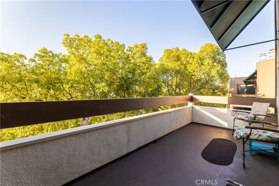 Balcony view overlooking trees with patio furniture.