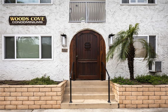 Front view of a condominium building with an arched wooden door and stucco exterior.