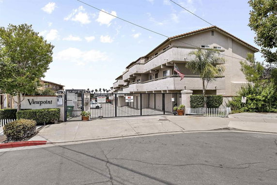 Front view of a multi-story residential building with a gated entrance.