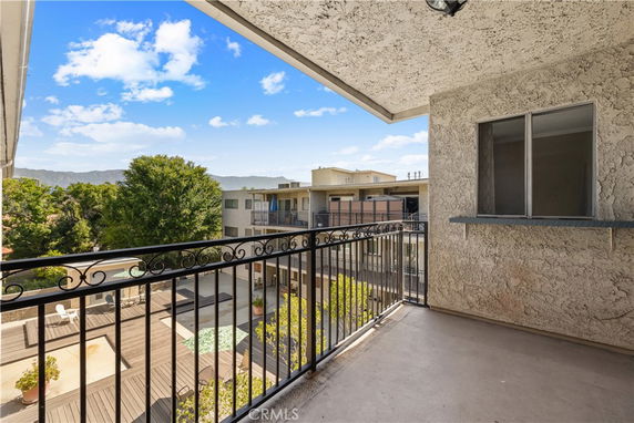 Apartment balcony overlooking a courtyard with views of surrounding buildings and mountains.
