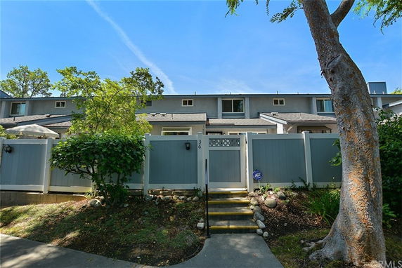Front view of a two-story townhouse with a gated entrance and surrounding trees.