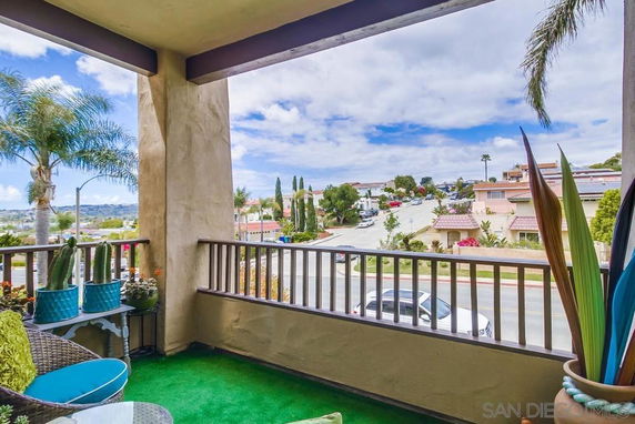 View from a balcony overlooking a residential neighborhood with palm trees and houses.