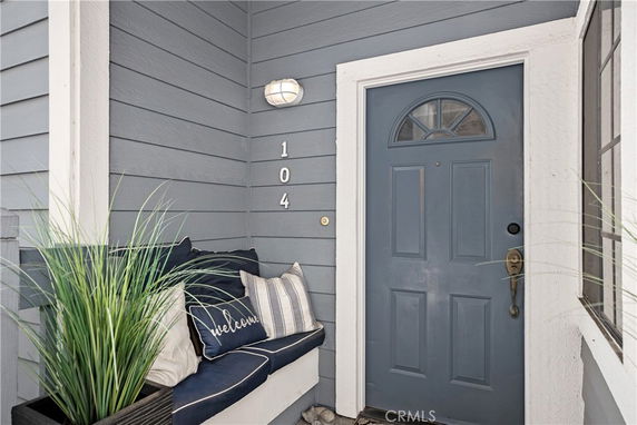 Front view of a house entrance with a blue door and seating area.