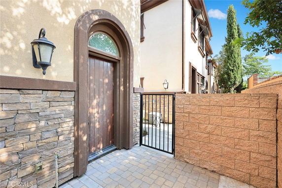 Front view of a house with a stone facade and arched wooden door.