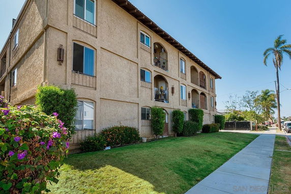Front view of a multi-story apartment building with balconies and arched windows.